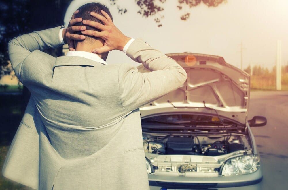 A Man Is Standing Next To A Broken Down Car With The Hood Up — Wilson's Towing In Dalby, QLD