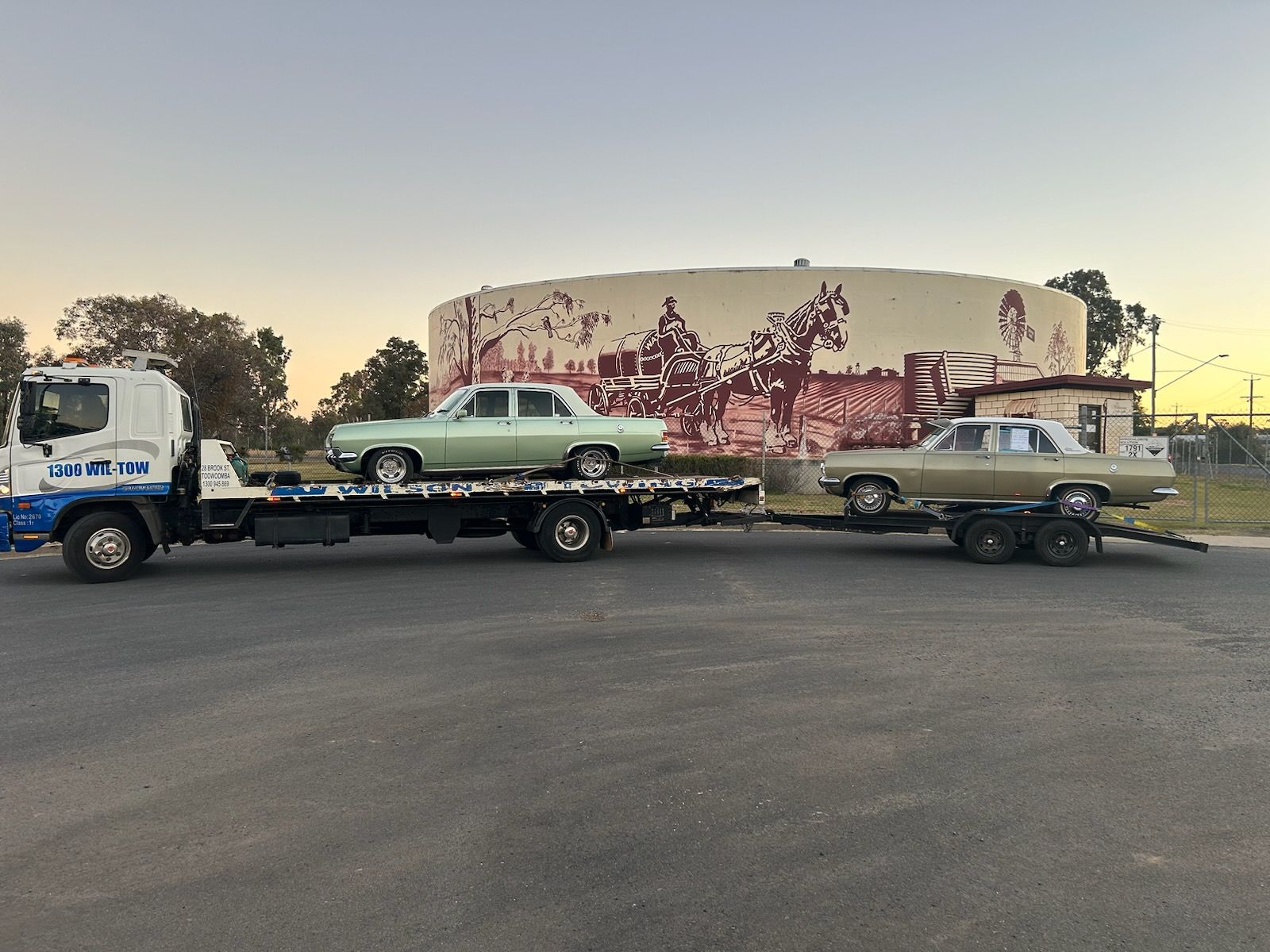 A Car With A Tow Truck In A Car Park — Wilson's Towing In North Toowoomba, QLD