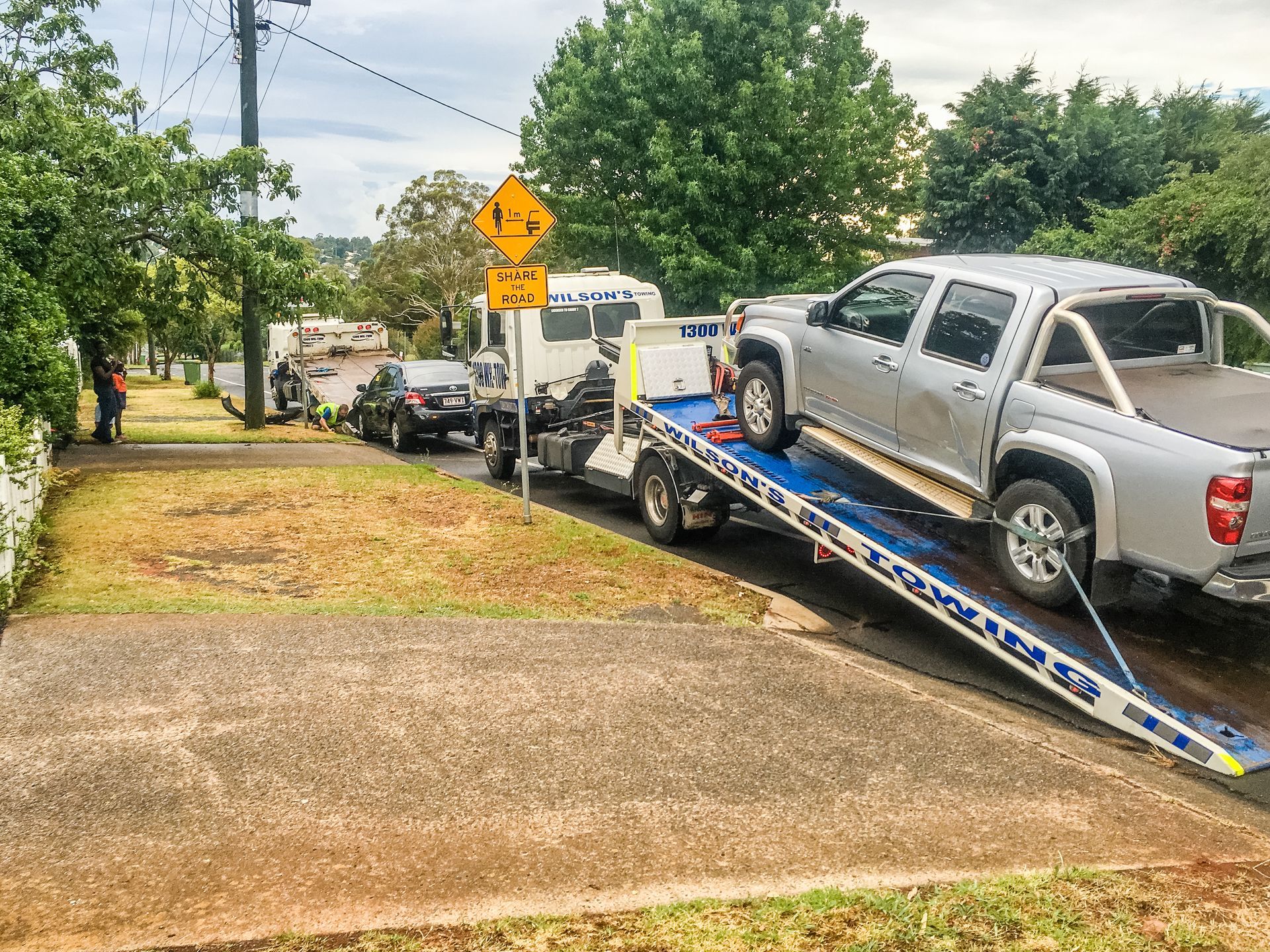 Silver Truck is Being Towed Down a Street by a Tow Truck — Wilson's Towing In Nambour, QLD