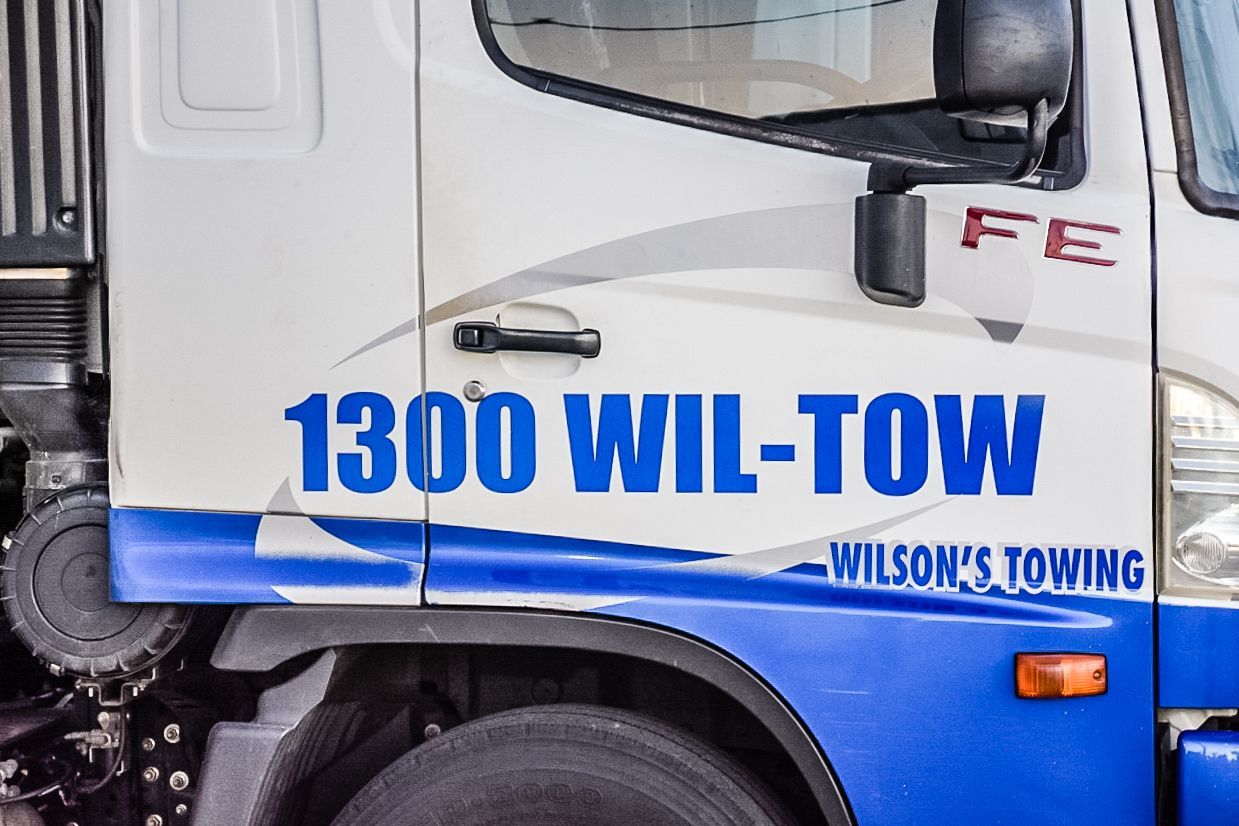 A Woman Is Talking On A Cell Phone In Front Of A Broken Down Car — Wilson's Towing In Gatton, QLD