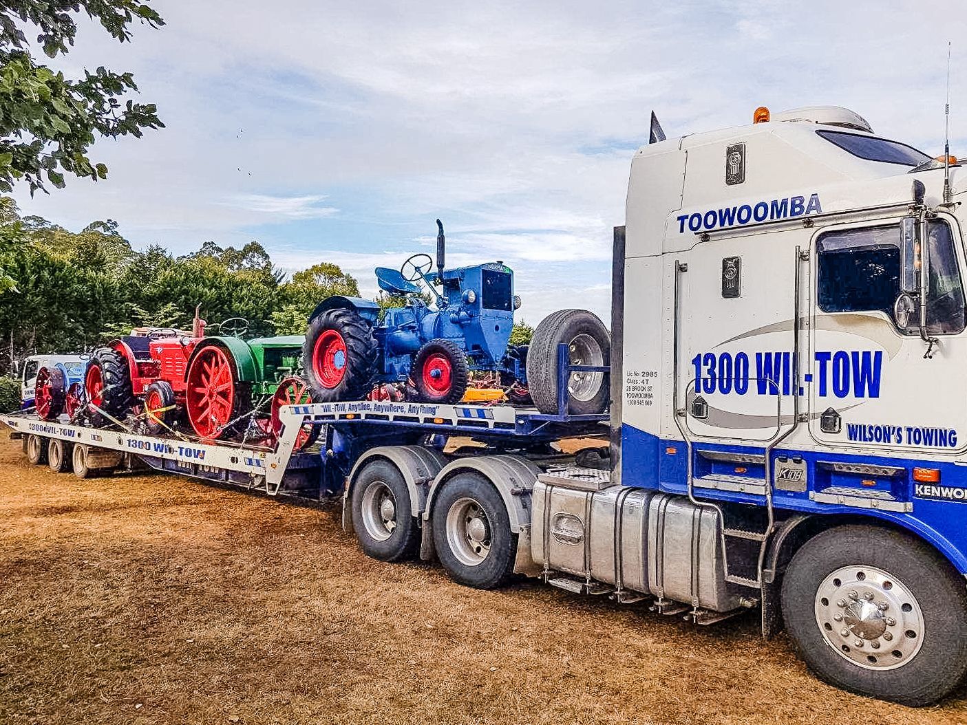 A Truck Is Carrying Two Vans On A Trailer On A Highway — Wilson's Towing In Caboolture, QLD