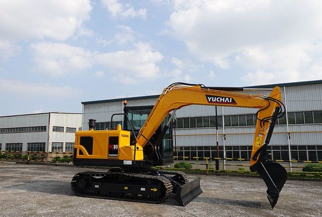 Yellow and black YUCHAI YC80 excavator parked outdoors on a sunny day.
