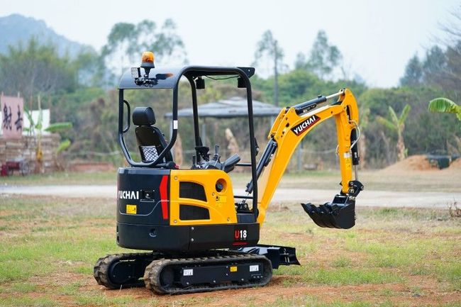 Small, yellow and black YUCHAI U18 excavator on tracks, outdoors.