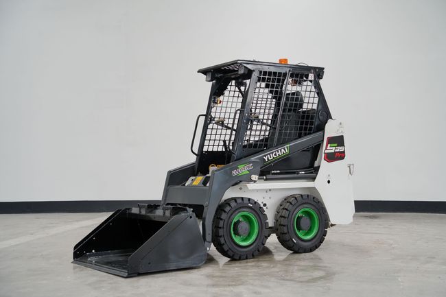 YUCHAI S35 skid-steer loader, black bucket, green tires, gray and white body, inside a studio.