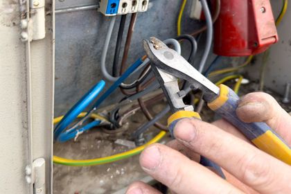 A person is working on an electrical box with a pair of pliers in Orlando, FL.