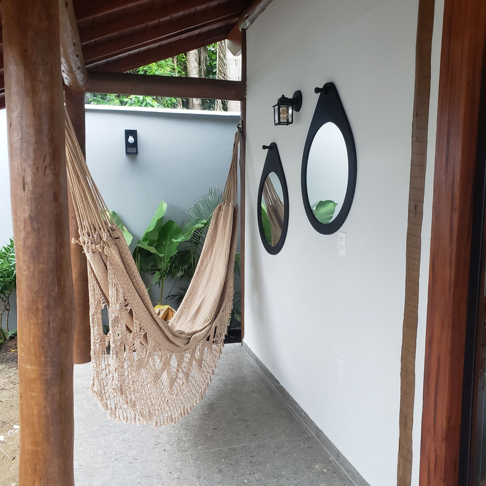 Uma rede pendurada na varanda ao lado de dois espelhos