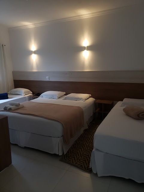 Um quarto de hotel com três camas e duas mesas de cabeceira.