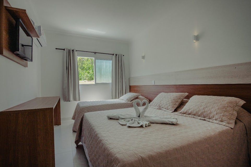 Um quarto de hotel com duas camas e uma televisão.