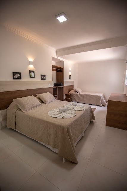 Um quarto de hotel com uma cama king size e duas camas de solteiro.