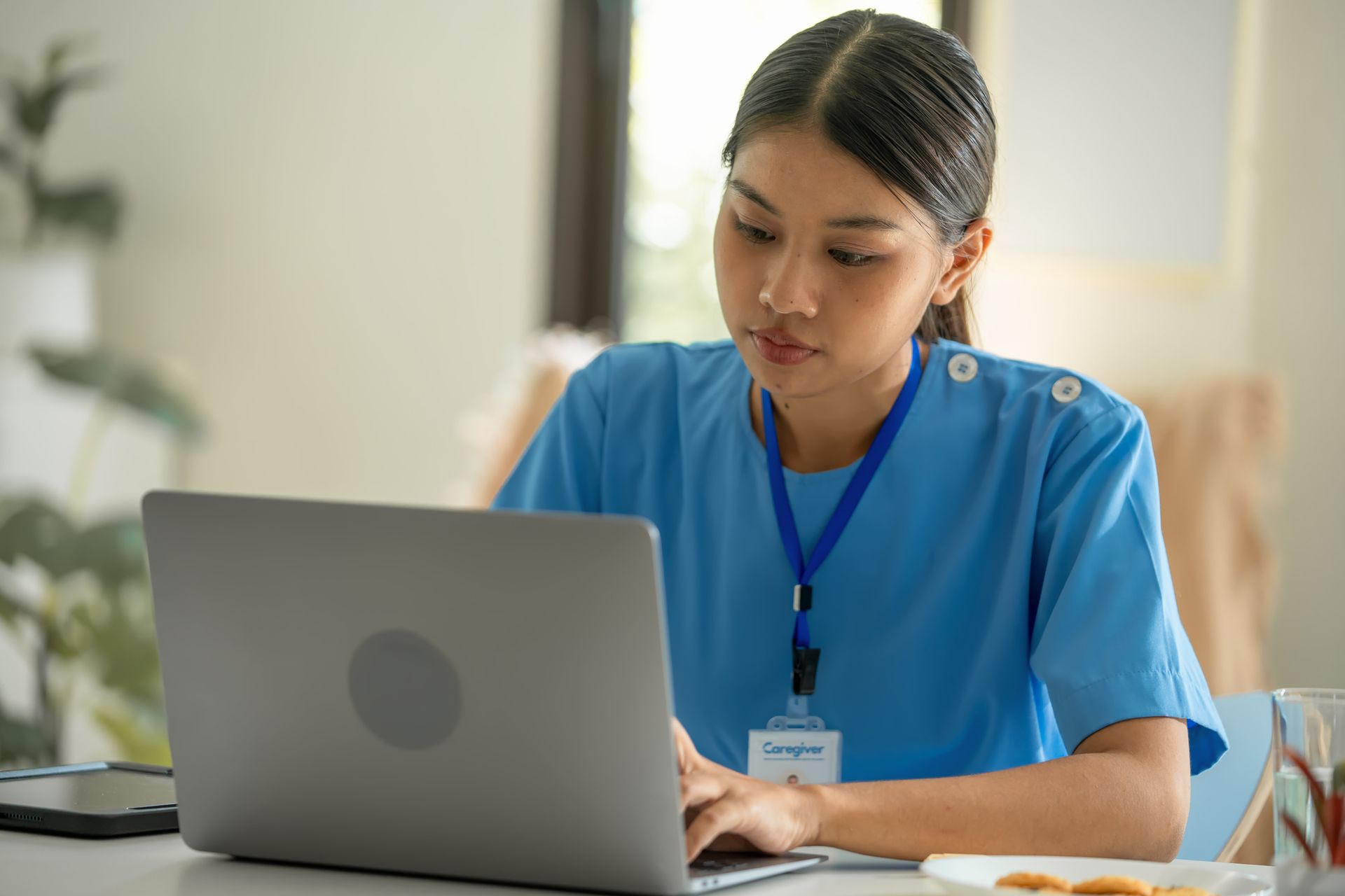 Woman in blue uniform working on a laptop indoors. Woman in blue uniform working on a laptop indoors.