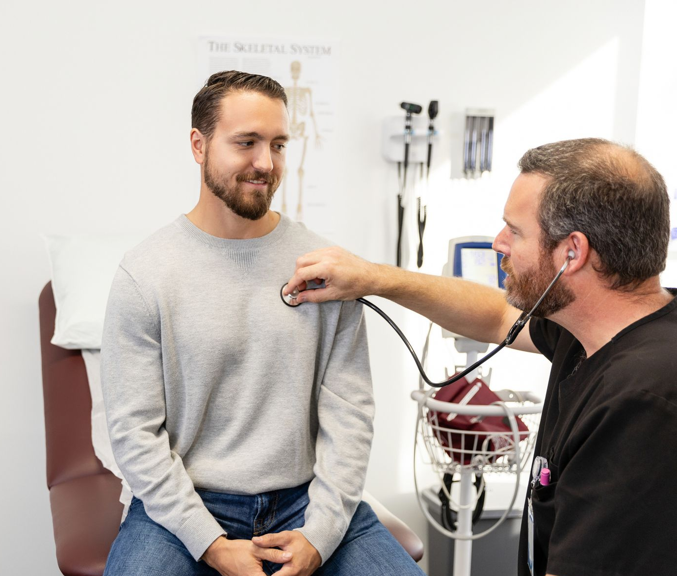 Doctor listening to patient's chest with a stethoscope in a medical examination room. Doctor listening to patient's chest with a stethoscope in a medical examination room.