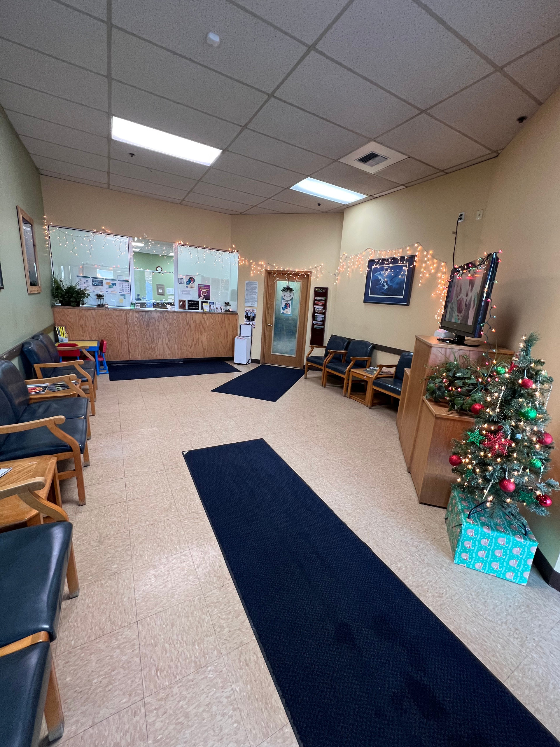 Waiting room with blue carpet runner, chairs, reception desk, and Christmas decorations.