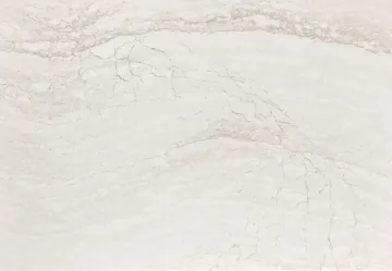 White marble countertop with swirling grey and beige veining.