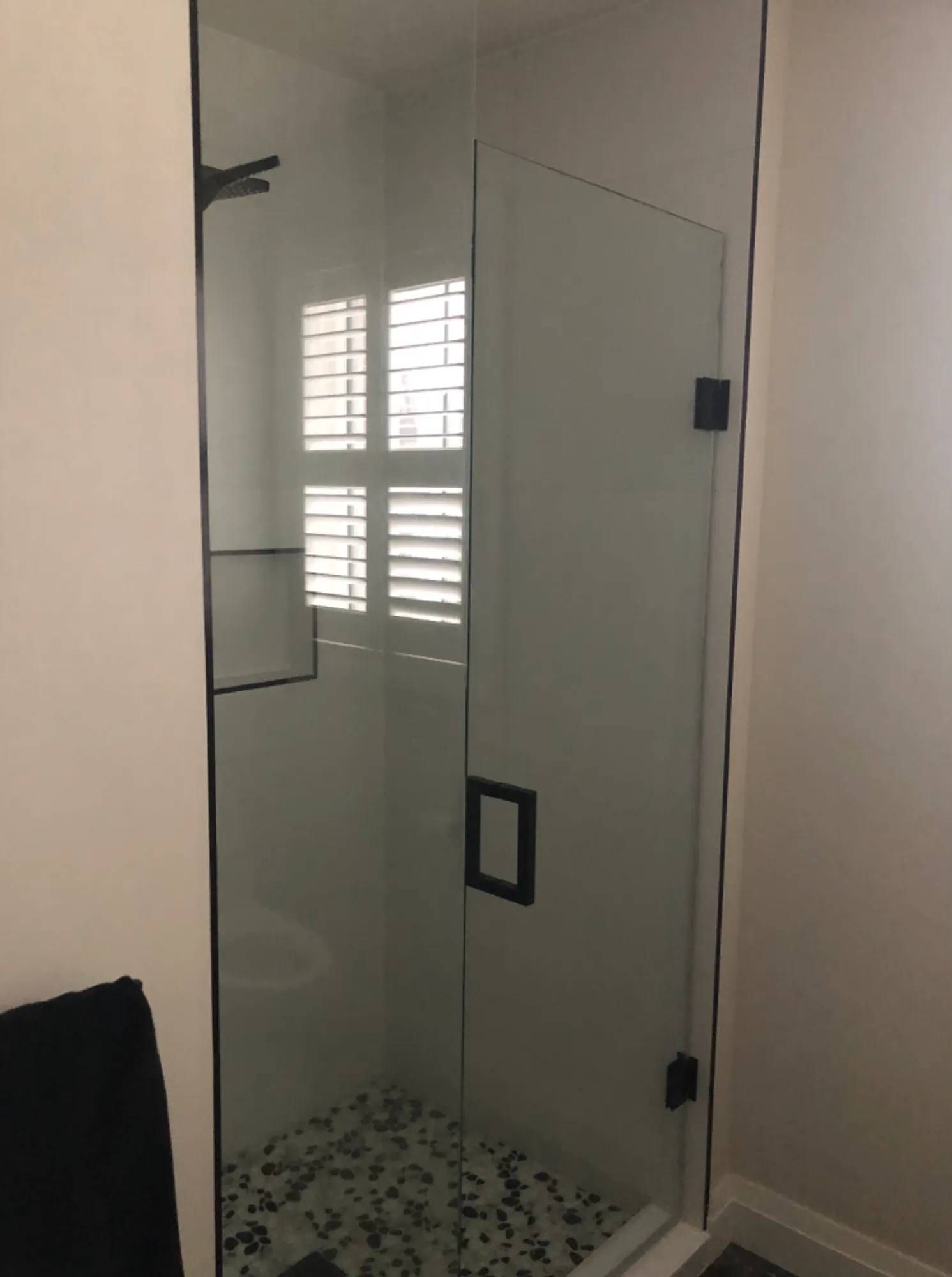 A bathroom with a shower and a window with shutters