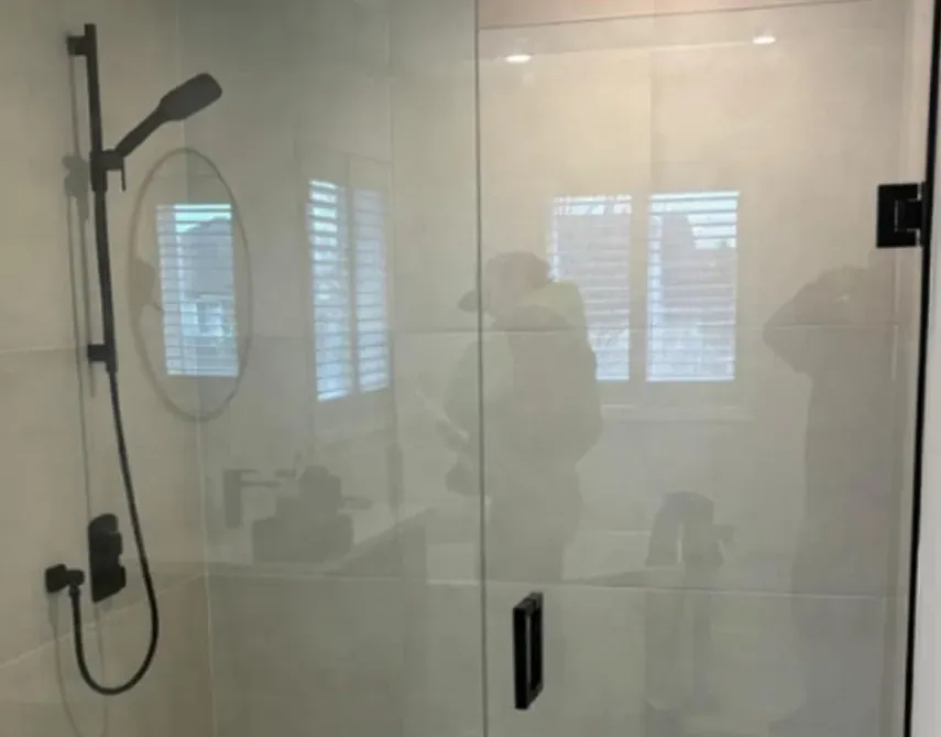 A bathroom with a shower and a mirror.