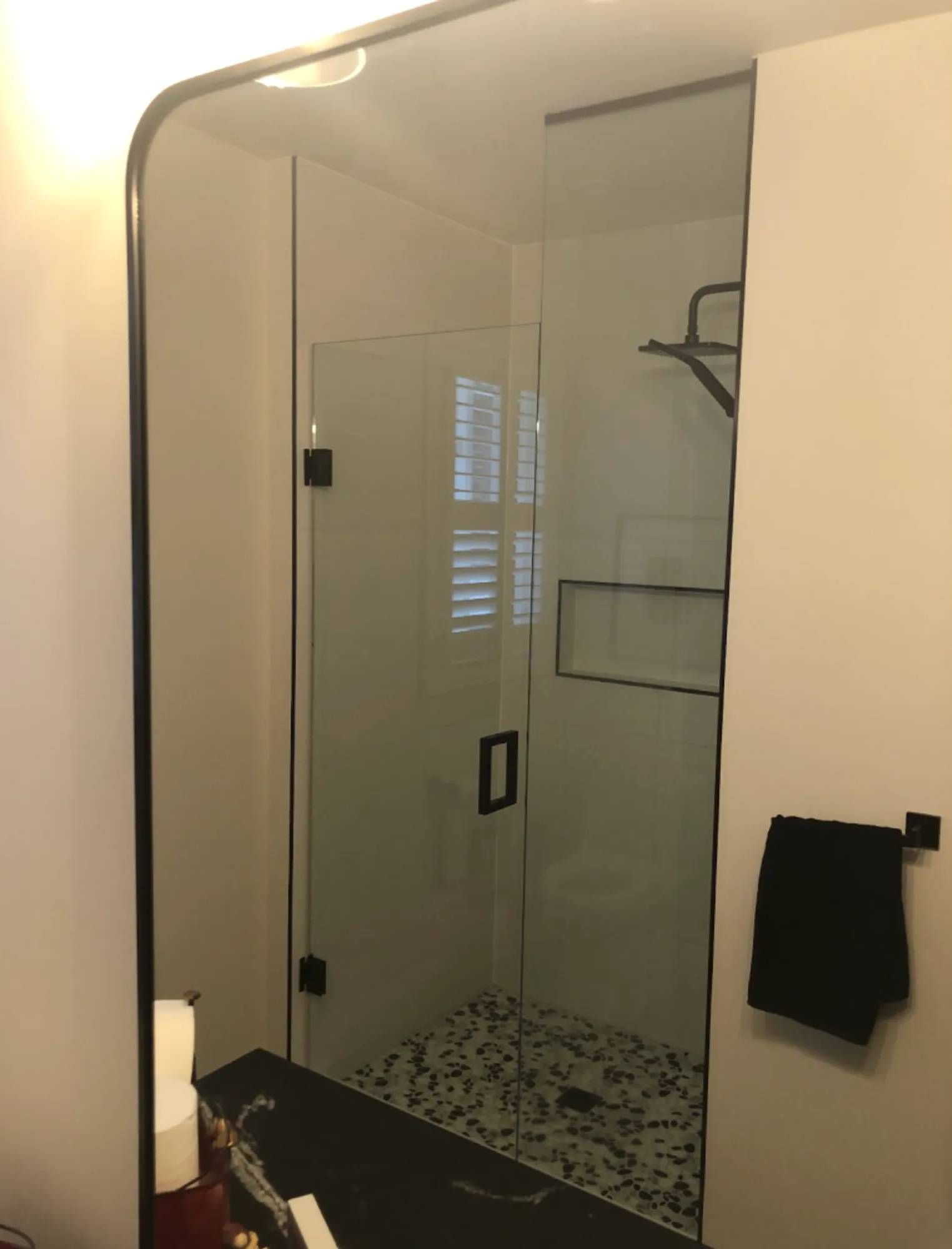 A bathroom with a walk in shower and a large mirror