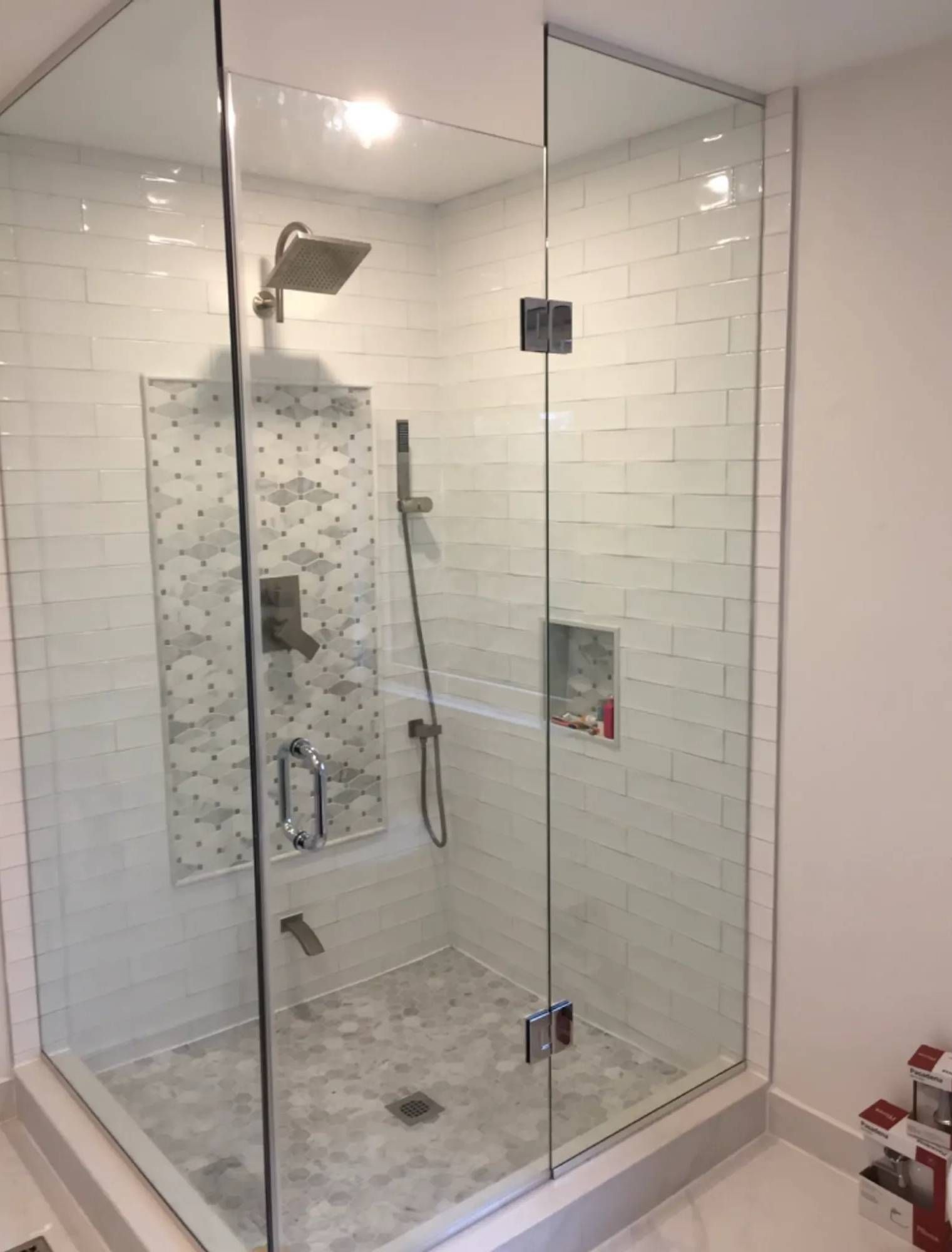 A bathroom with a walk in shower with a glass door.