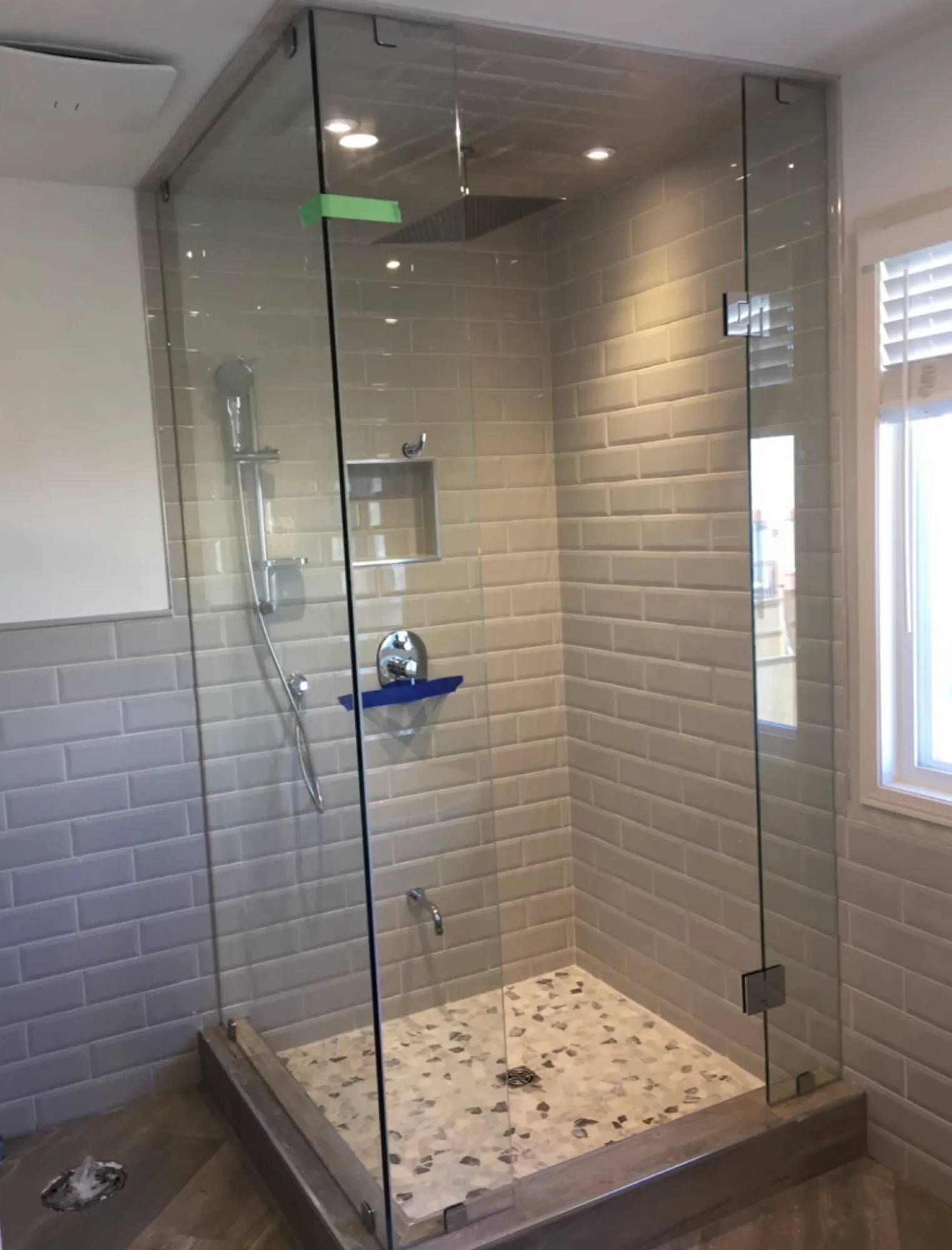 A bathroom with a walk in shower with a glass door.