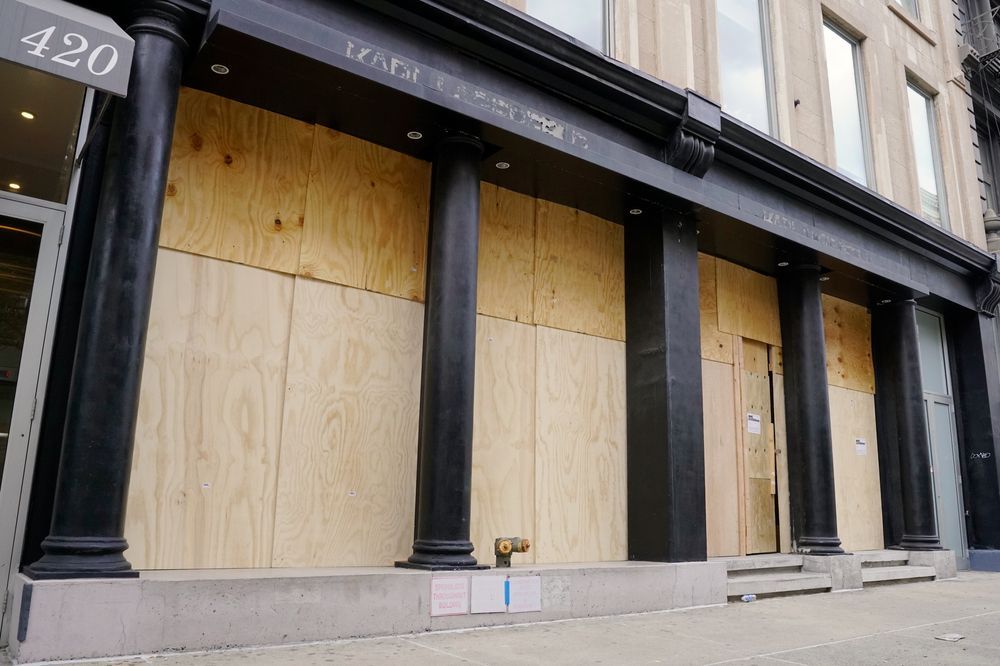 The front of a building with wooden boards on the windows.