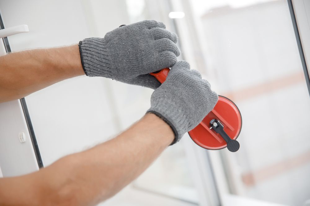 A man wearing gloves is installing a glass door.