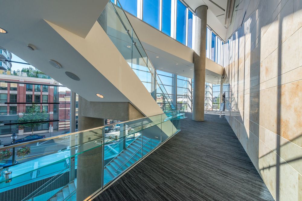 A long hallway with stairs and a glass railing in a building.