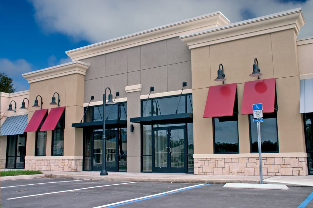 A building with red awnings and a parking lot in front of it