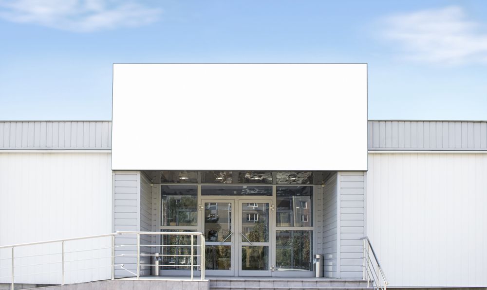 A large white billboard is hanging on the side of a building.