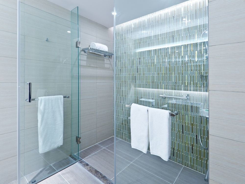 A bathroom with a walk in shower , sink , and towels.