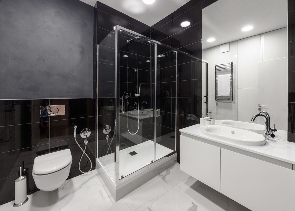 A bathroom with a toilet , sink , shower and mirror.