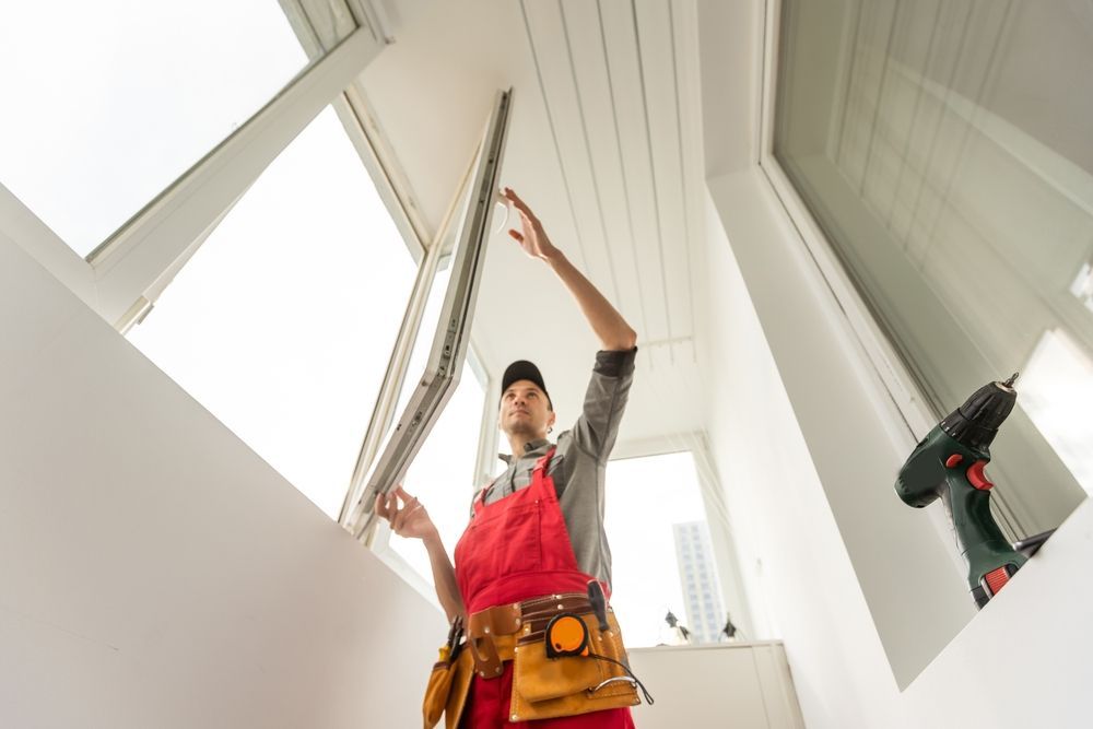 A man is installing a window on a balcony.