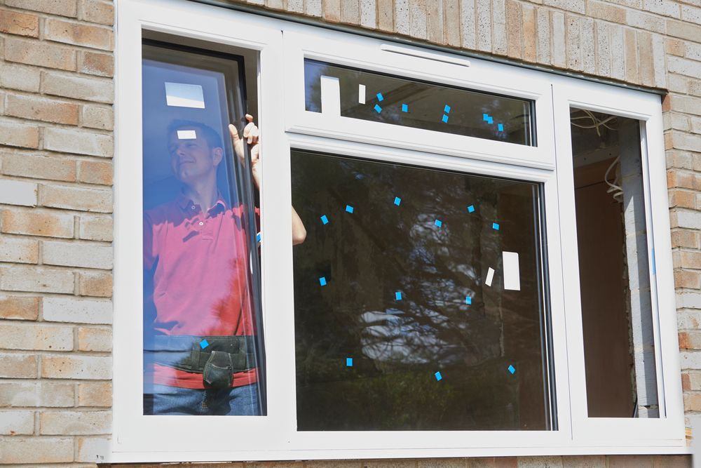 A man is installing a window on a brick building.