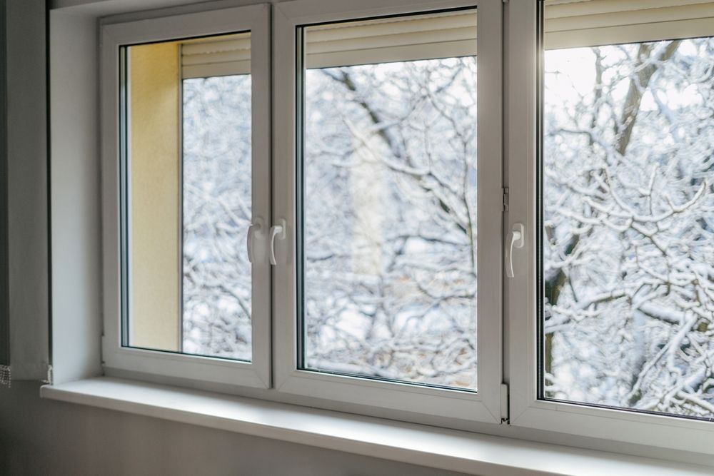 There is snow on the trees outside of the window.