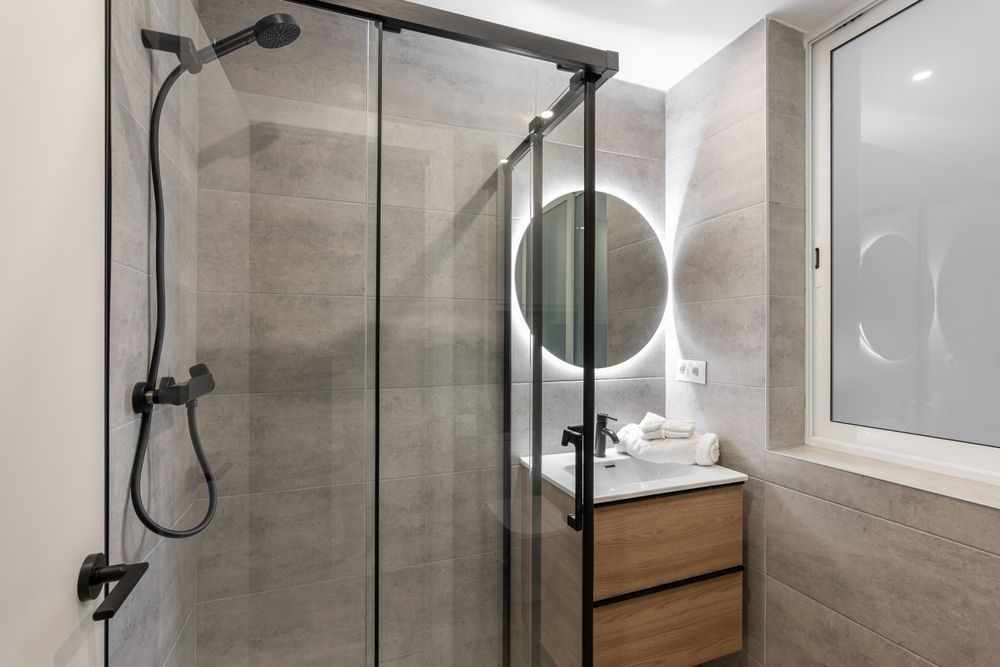 A bathroom with a shower , sink and mirror.