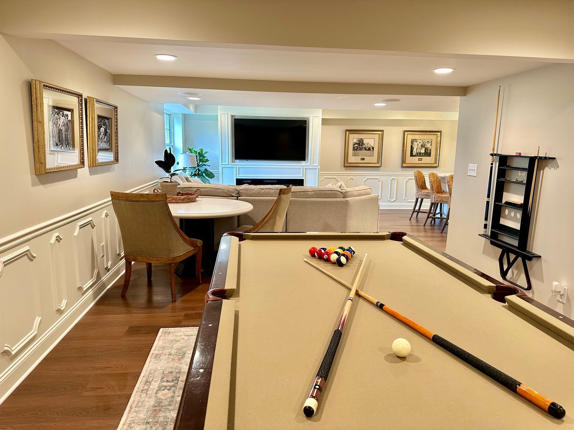 Basement recreation room with pool table, seating area, and wall art overlooking a TV.