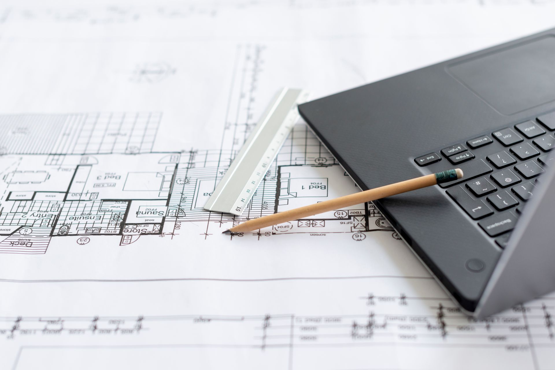 Laptop and pencil on architectural blueprints on a desk