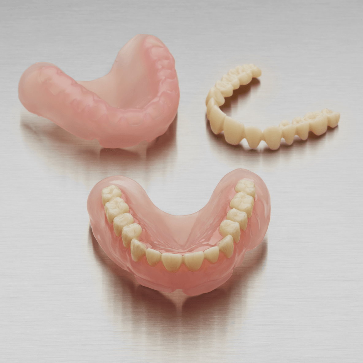 Three dentures are sitting on top of each other on a table.