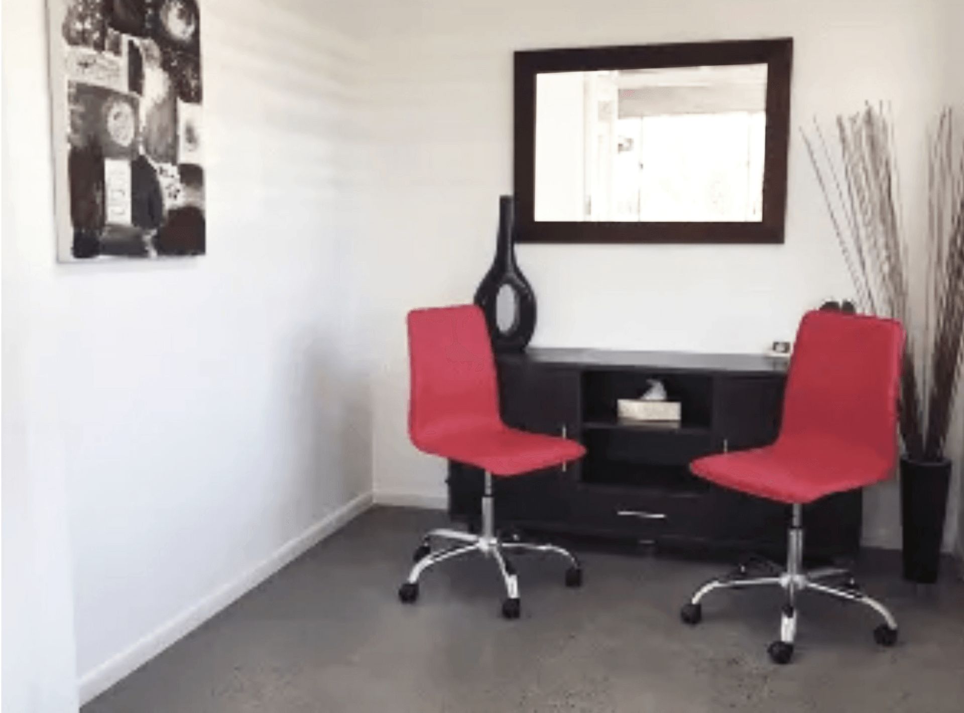 A room with two red chairs and a mirror on the wall