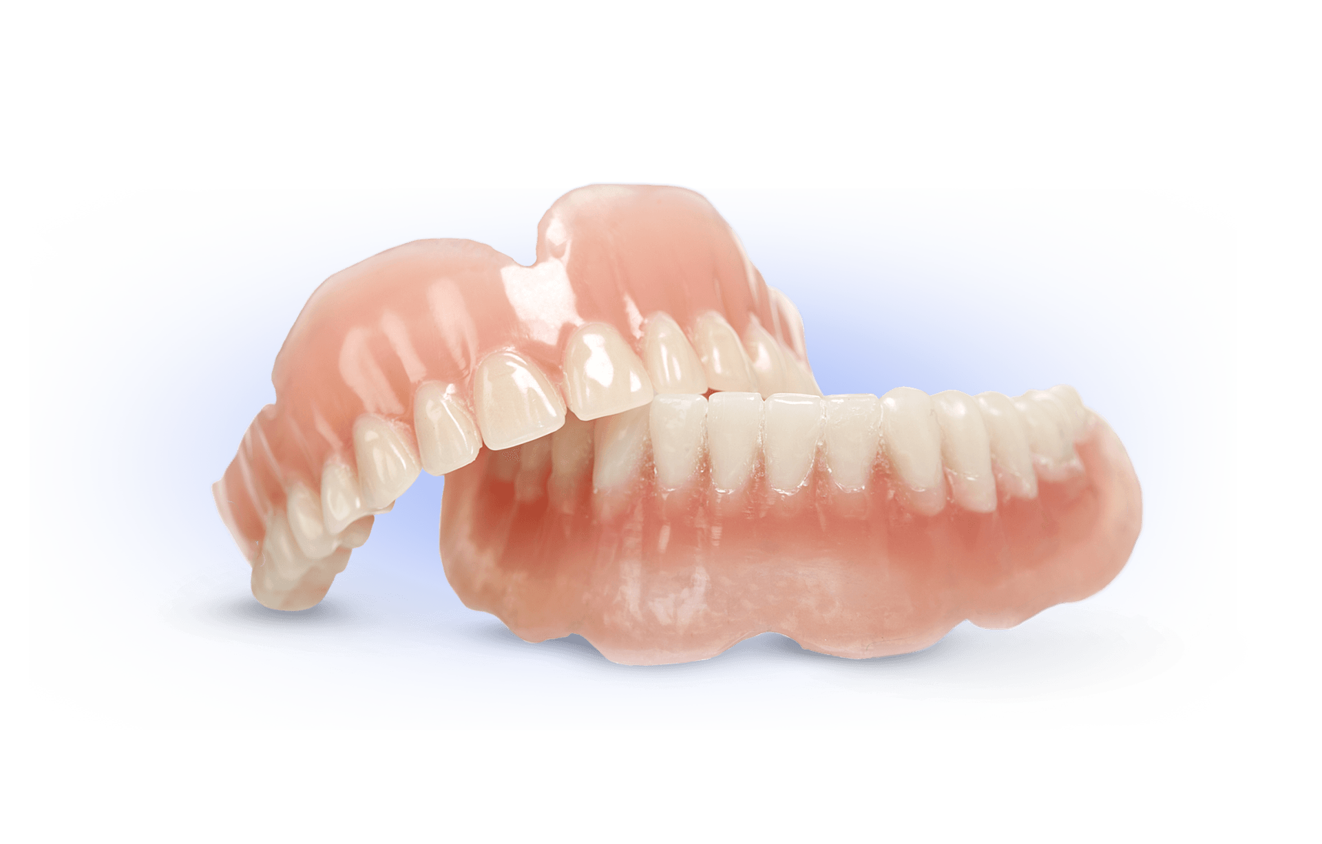 A pair of dentures sitting on top of each other on a white surface.