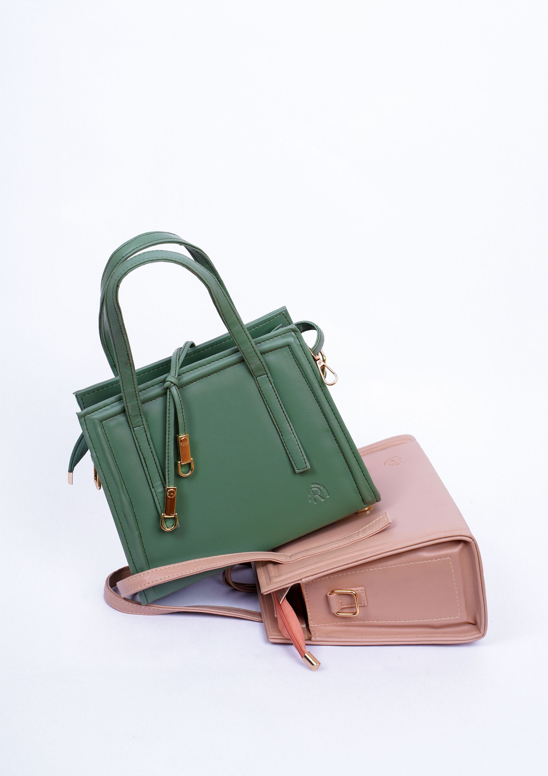 Dos pequeños bolsos, uno verde y otro rosa, apilados sobre un fondo blanco.