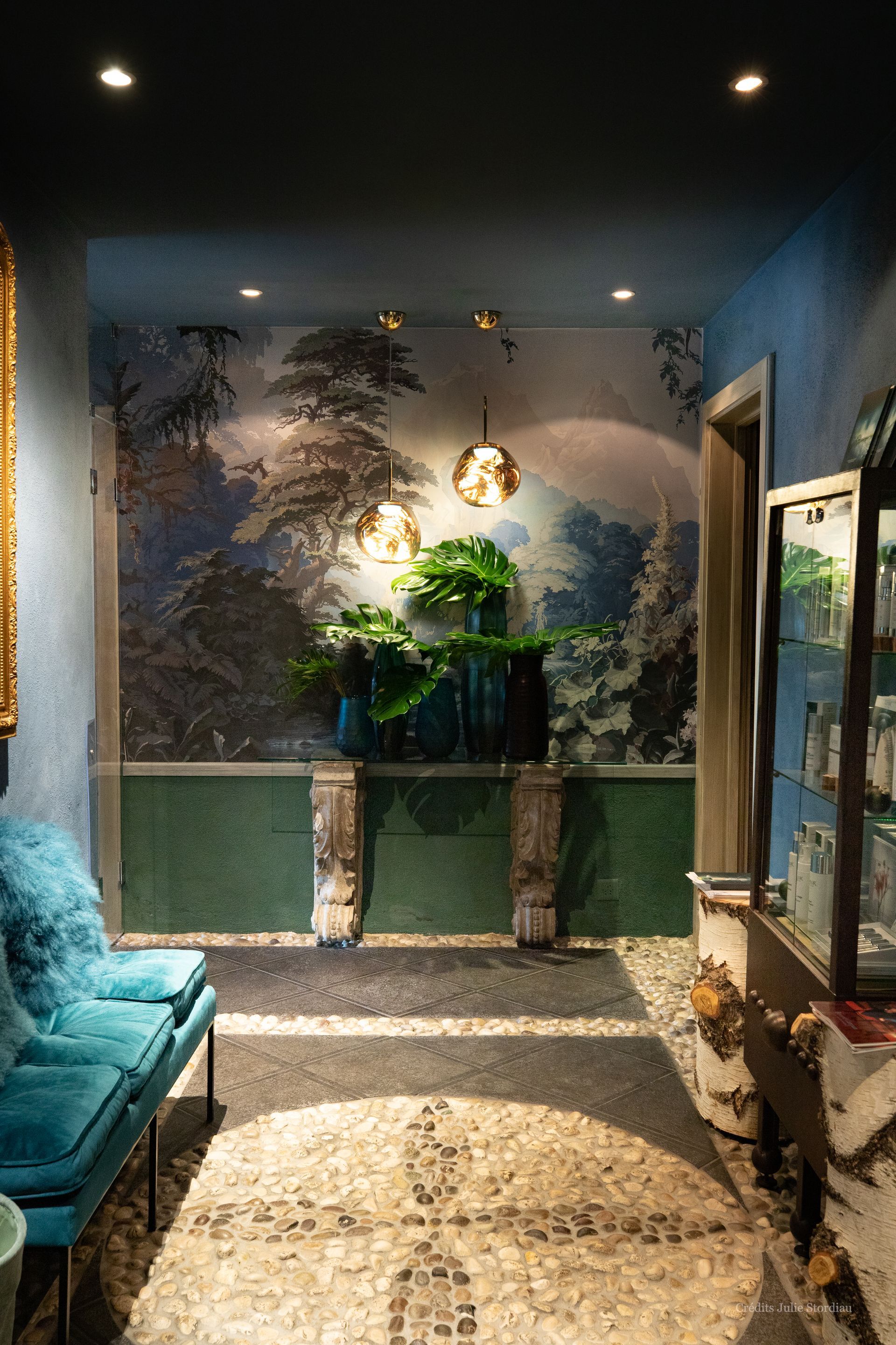 un couloir avec un canapé bleu , un tapis , une table et un miroir .