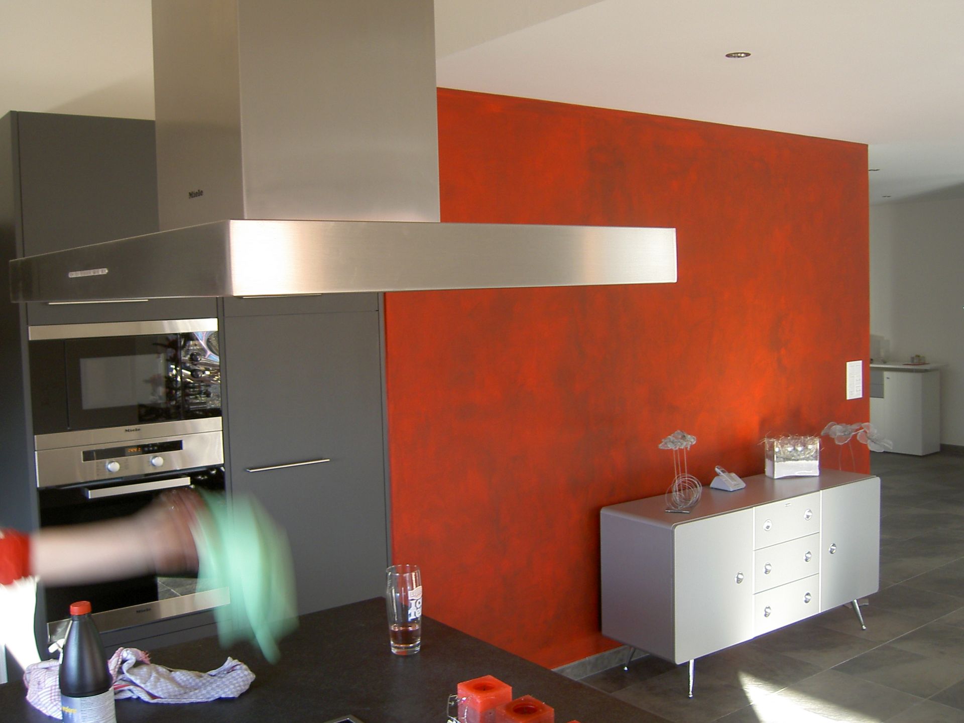 une cuisine avec un mur orange et une table blanche.