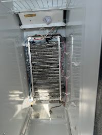 Interior of a refrigerator showing a heavily frosted evaporator coil.