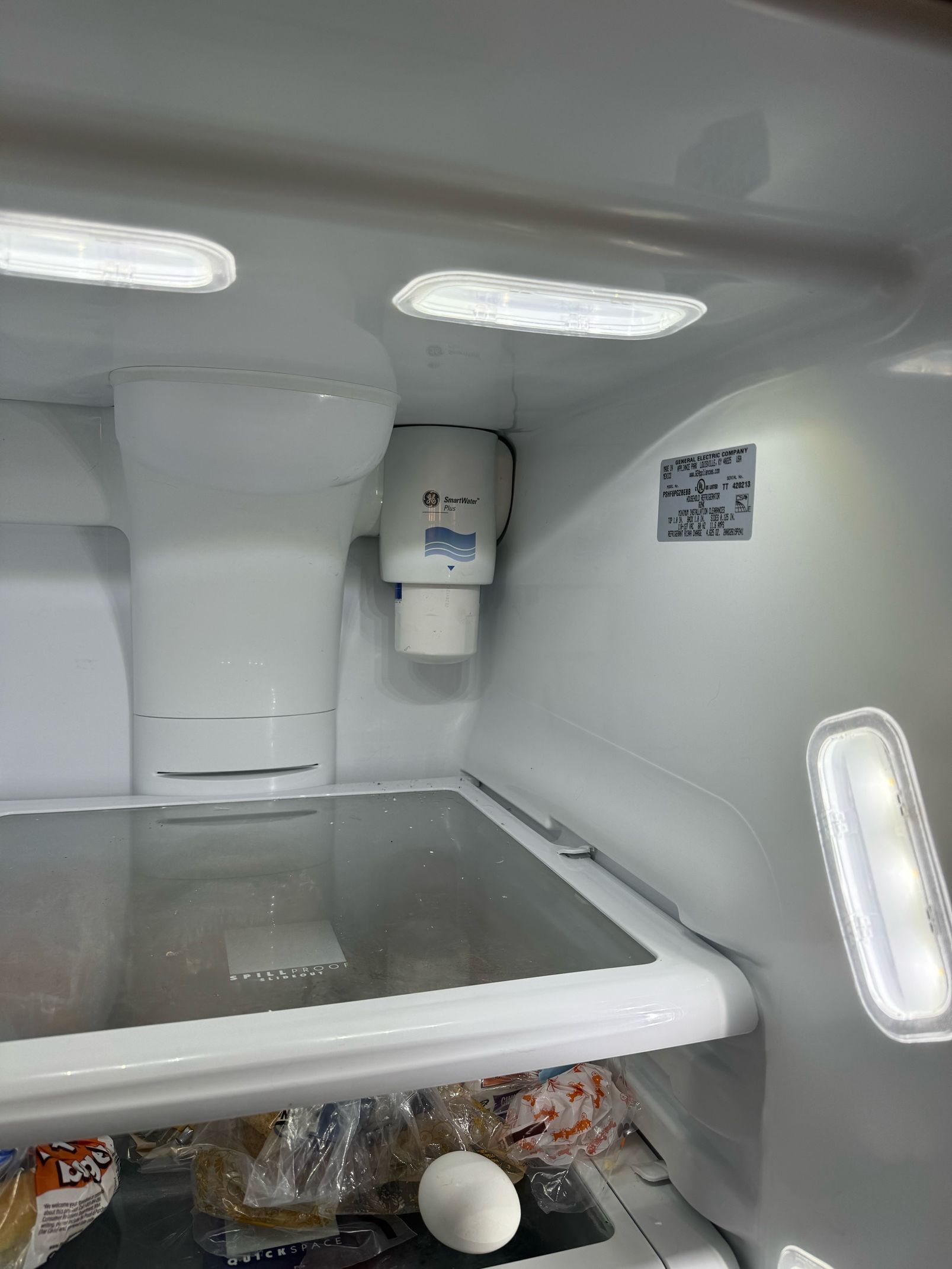 The inside of an empty refrigerator with a ice maker.