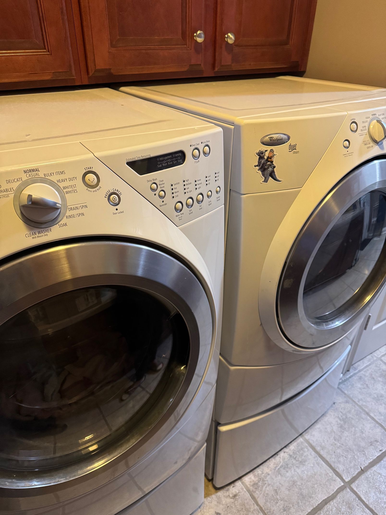 Two white Whirlpool front-load washers and dryers with stainless steel doors, set in a laundry room.