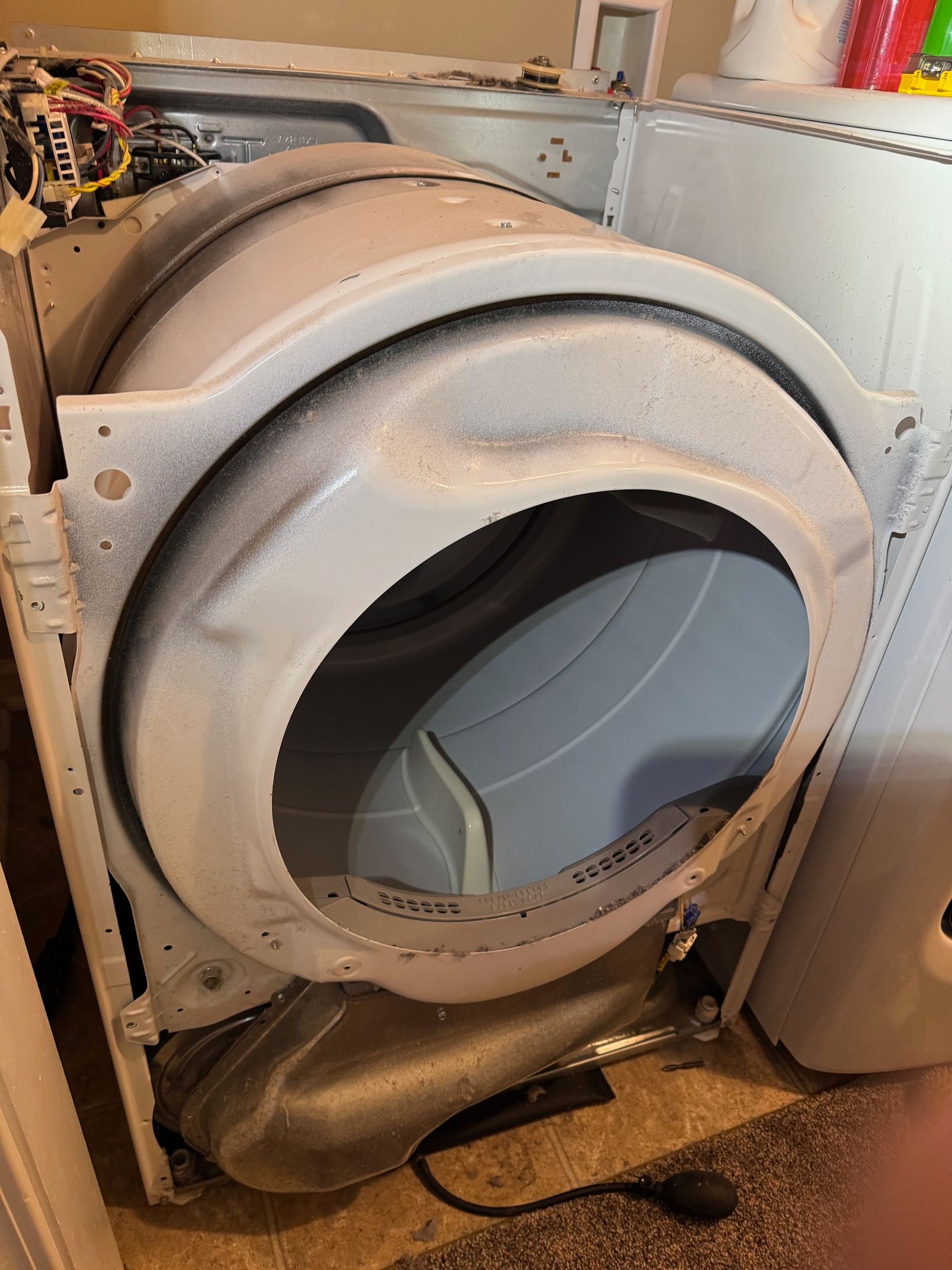 Open dryer drum interior, coated in lint, with the dryer's housing visible.