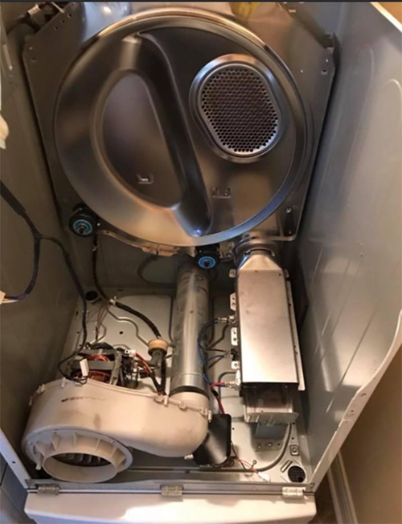Interior view of a disassembled dryer machine, showing the drum, blower, and heating element.