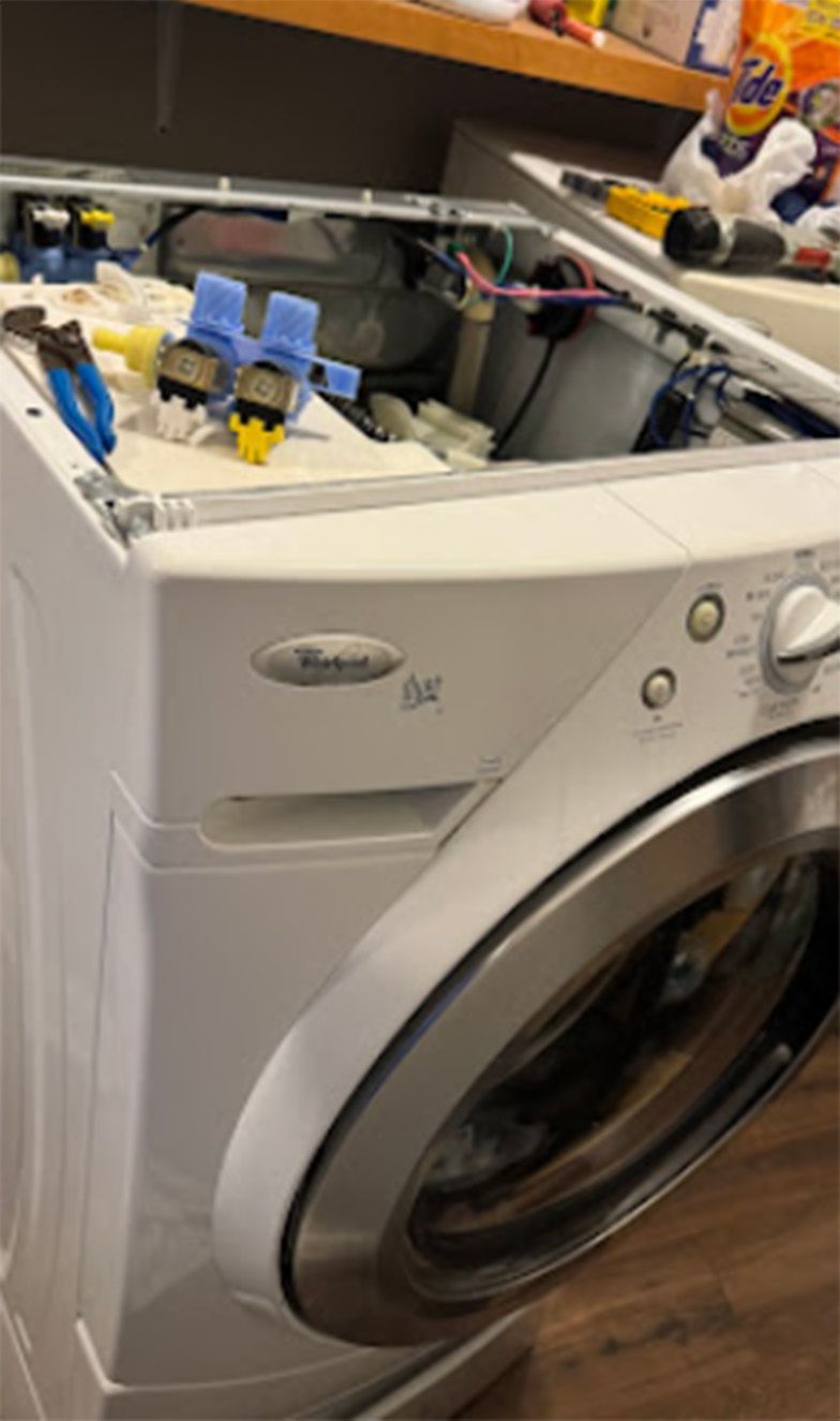 White Whirlpool washing machine, top open, interior components visible.