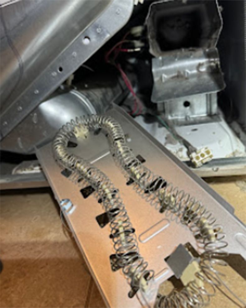 A disassembled dryer with a heating element exposed; metal components and wiring visible.