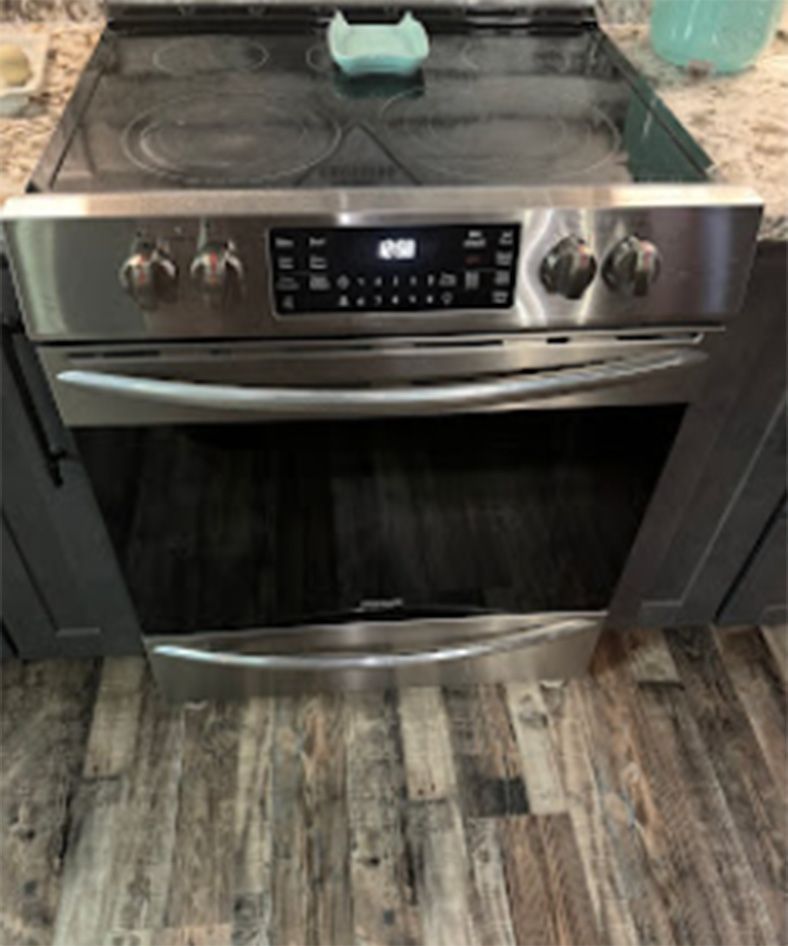 Stainless steel oven with digital display and cooktop in a kitchen.