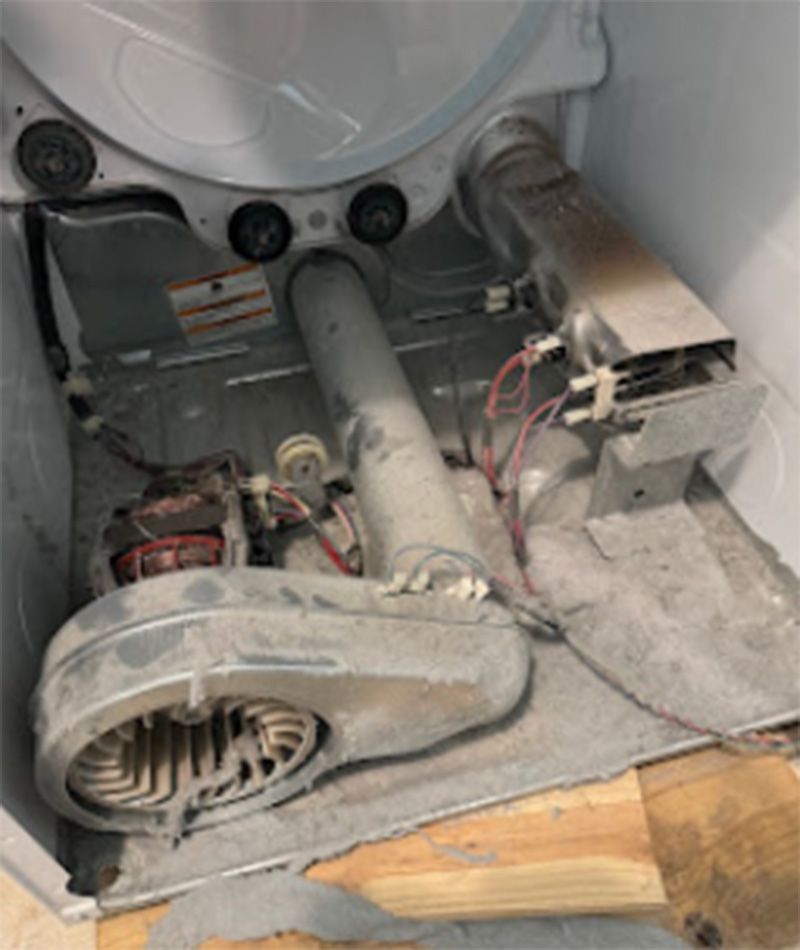 Interior of a dryer with significant lint buildup. Components like the blower fan and vent are visible.